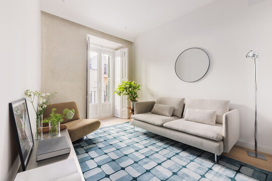 Living room with teal rug, mustard armchair and open balcony