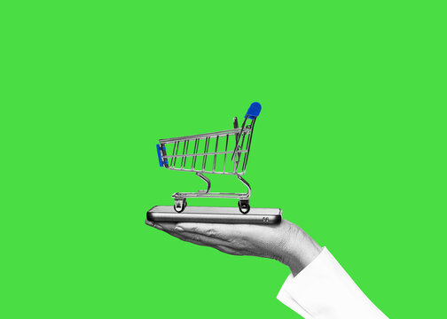 One hand holds shopping cart isolated on free green screen background. Digital, online shopping on the internet.