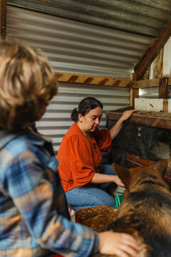 Mother and son and a dog guarding chickens inside the henhouse.