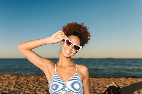 Young woman smiling in heart shaped sunglasses on beach vacation