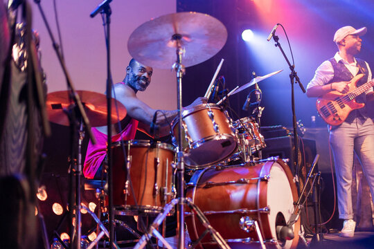 Drummer playing live music on stage smiling
