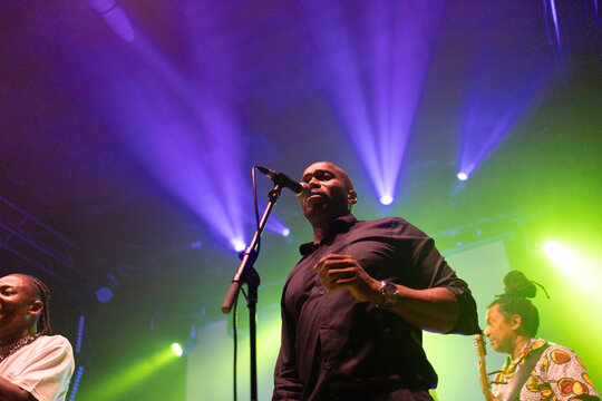 Singer performing on stage with colorful light beams