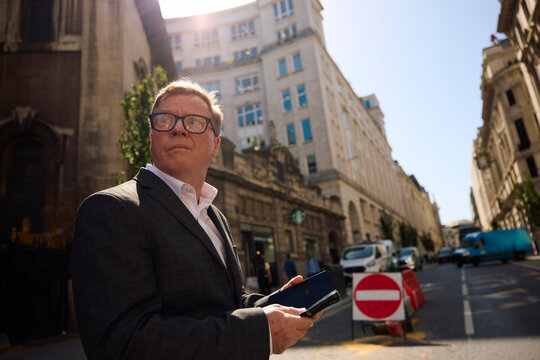 Businessman stands on the street in London, looking around