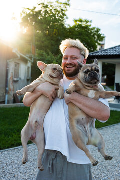 Man Holding Two French Bulldogs In Evening Sunlight