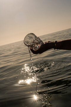 A hand holds a glass and fills it with seawater
