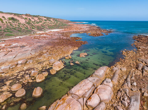 Coastal inlet surrounded by colorful granite boulders 