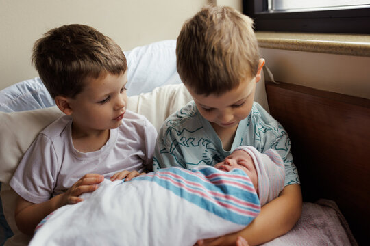 Young Siblings Cradle Newborn