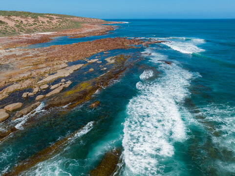 Waves crashing onto rocky reefs along a remote rugged coastline