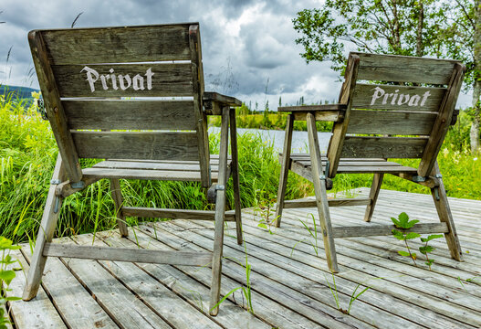 Zwei Holzst&uuml;hle auf einer Holzterrasse an eine schwedischen see mit der Aufschrift Privat