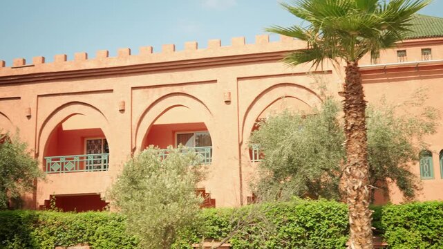 Terracotta Arched Building With Balconies and Lush Garden Moroccan Style Courtyard Architecture