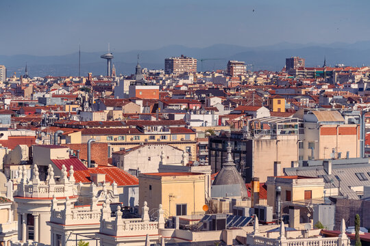 Elevated view over central Madrid rooftops with Faro de Moncloa and distant mountains