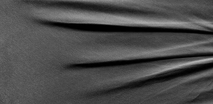 close-up abstract textured dark gray fabric surface with soft folds and shadows.