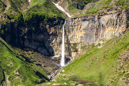 Sissu Waterfall wide landscape view plunging down rocky cliff into lush green Himalayan valley in Lahaul Himachal Pradesh