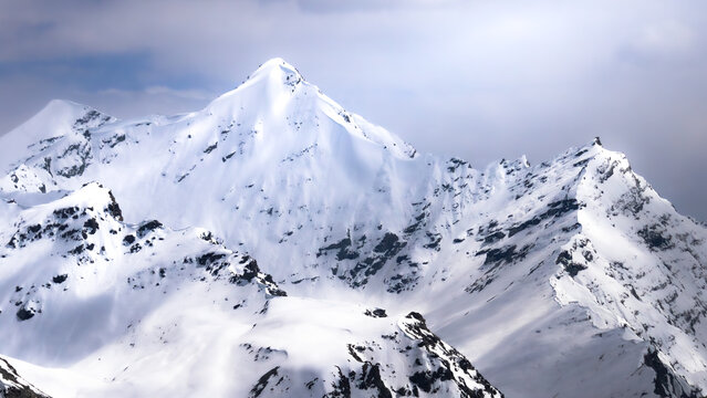 Snow-covered Himalayan mountain peaks under dramatic clouds in a pristine alpine winter landscape