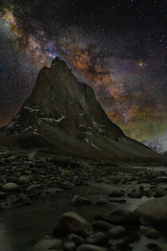 Milky Way galaxy rising above Gonbo Rangjon himalayan mountain monolith at night with stream foreground in Zanskar Ladakh starry sky