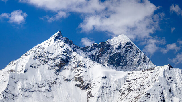 Majestic Snow Covered Mountain Peaks Against Clear Blue Sky, Sharp Glacier Peaks in High Altitude Himalayan Range On a Bright Sunny Day