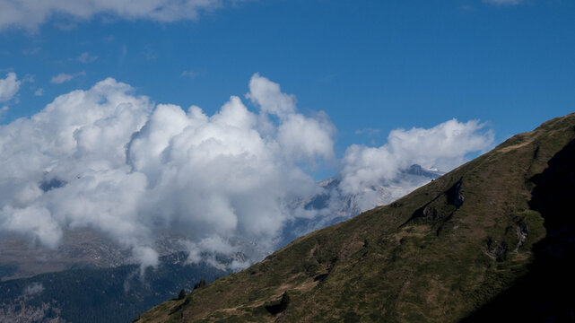Breathtaking high-altitude landscape in the Valais region of Switzerland, featuring a dramatic, steep green mountain ridge. 