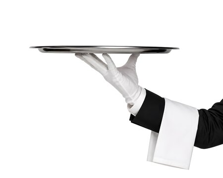 A hand in a white glove holds a silver tray. This takes place in a restaurant setting during meal service. The focus is on the tray and the hand holding it