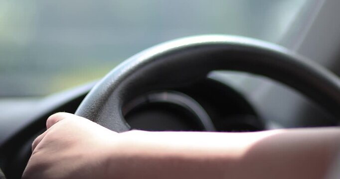 Close-up of hands practicing steering while learning to drive. Concept of beginner driver training, steering control, safe driving, driving school, road safety, and transportation
