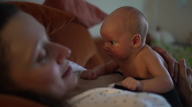 Curious newborn baby lifting its head for the first time during tummy time on its mother's chest, strengthening neck muscles and bonding in a moment of early development and discovery