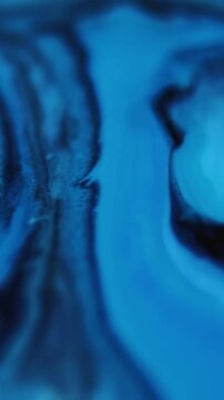 Vertical video. Ink water. Chemical fluid. Defocused blue color paint enamel marble wet texture growing on abstract art background.