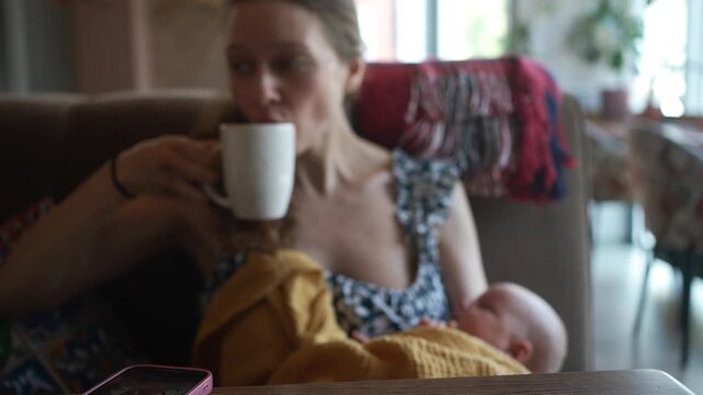 Young mother multitasking in a coffee shop, hastily sipping her beverage while holding her sleeping newborn, trying to have a quick break before the infant wakes up and demands attention