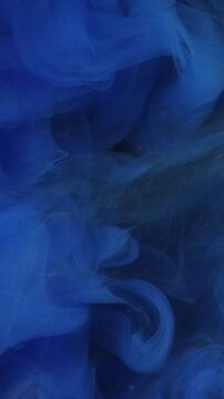 Vertical video. Underwater blend. Flowing paint. Defocused blue smoke ethereal mist water wet splash chemical liquid on abstract art background.