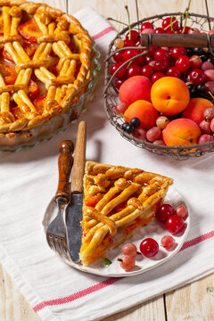 Apricot pie decorated with dough ornament and a metal basket with fruits and berries.