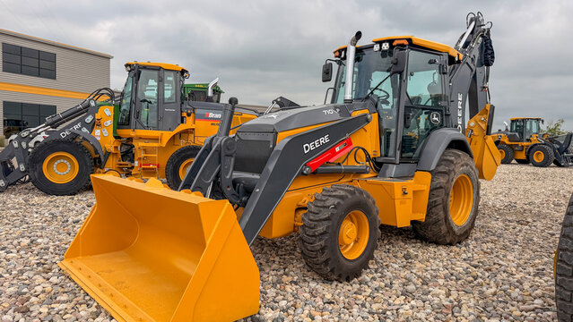 Regina, Canada - July 20, 2026: John Deere 710P backhoe loader displayed at equipment dealership lot with multiple yellow construction machines