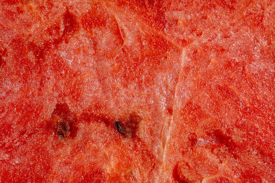 Macro closeup of ripe watermelon flesh with embedded black seeds