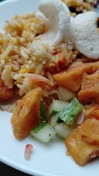 Traditional spiced rice with golden fried potatoes, fresh vegetables, and crackers served on a white plate. A colorful homemade meal highlighting authentic flavors, cultural cuisine, and hearty comfor