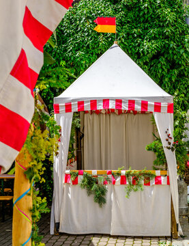 Festive market stall decorated with greenery and flags in a lively outdoor setting during summer