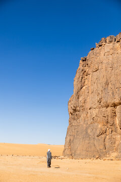 Guide Standing Before a Sheer Rock Cliff