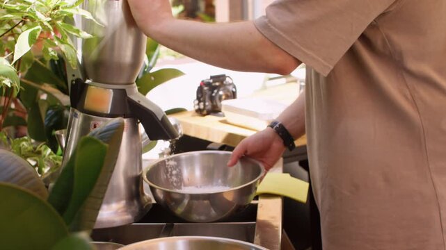 Outside serving. Automated ice crushing. Unrecognizable male hands using electric machine making refreshment beverage in cafe.