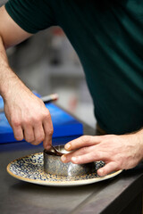 Fototapeta premium Close-up of chef hands shaping tartar in a ring mold with a spoon