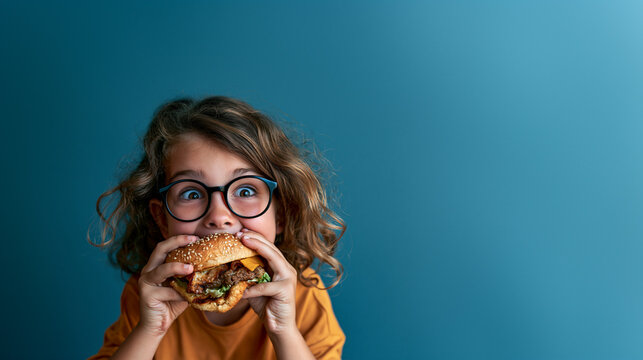 child enjoying a delicious burger, happy kid eating a hamburger, cheerful child enjoying a tasty meal