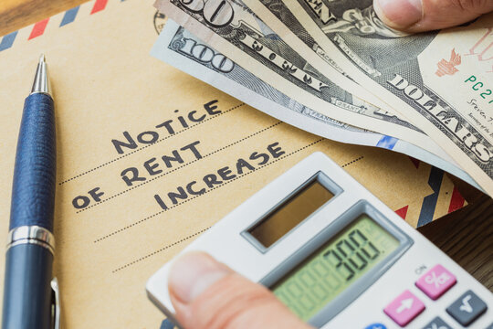 Rent increase notice concept with text on envelope, US Dollar cash, calculator and pen. Real estate housing expenses, home budget costs and domestic financial inflation.