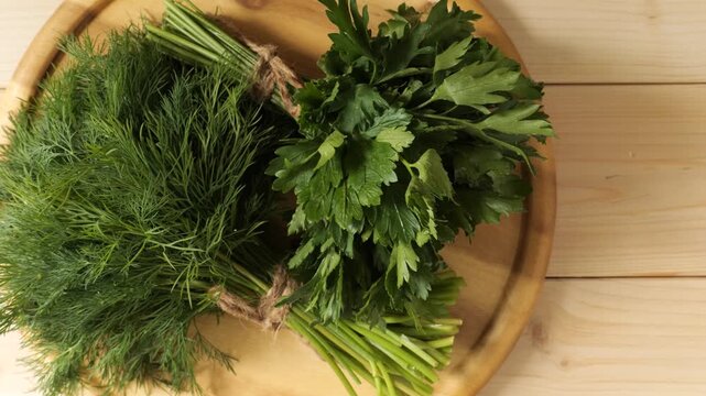 Fresh dill and parsley bunches on a wooden cutting board