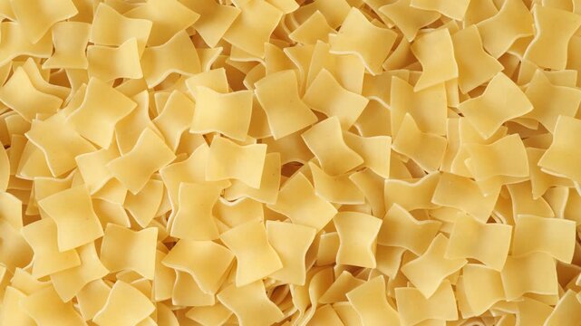 Uncooked quadretti pasta slowly moving top view
