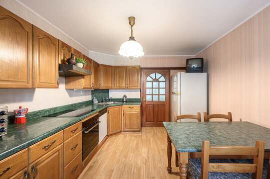 kitchen features oak cabinets with arched panel doors, green granite countertops, built‑in oven, dishwasher, microwave, sink, dining table with wooden chairs