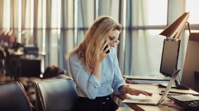 Businesswoman Talking On Smartphone Working On Laptop. Professional Communication And Multitasking. Corporate Job