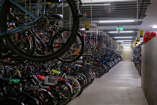 Germany, Munster, June 15 2026. train station. Deep perspective shot along an aisle in an underground bicycle parking station showing multi level bike racks extending into the distance.