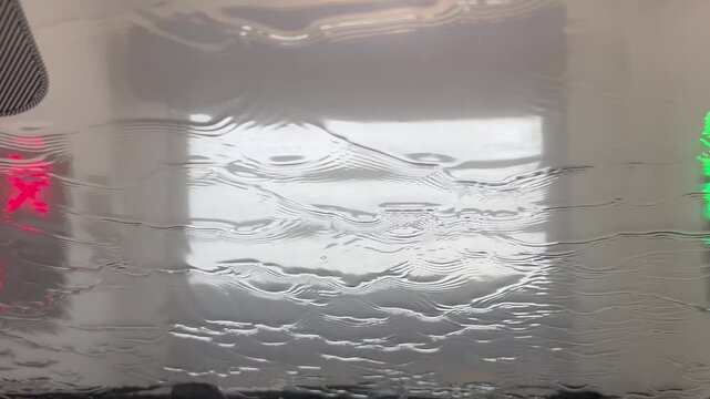 Car wash water rinsing over car windshield interior view