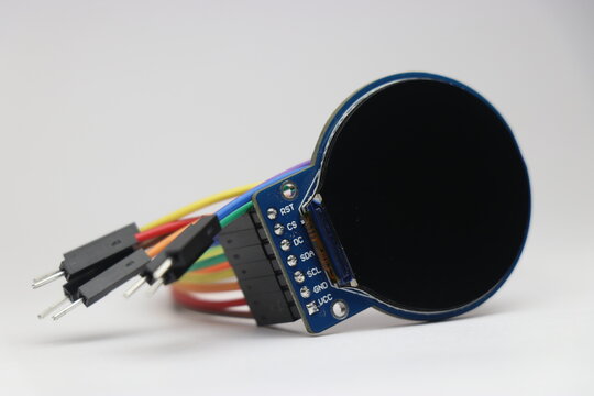 Round TFT LCD screen connected with jumper cables used in electronic projects