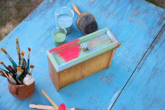 Painting a wooden furniture outdoors, an eco-friendly re-use business.