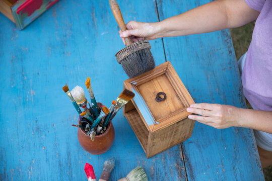 Painting a wooden furniture outdoors, an eco-friendly re-use business.