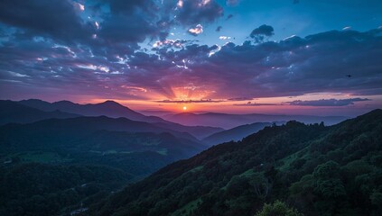 Obraz premium Breathtaking sunset over the rolling mountain ranges with vibrant purple and orange clouds.