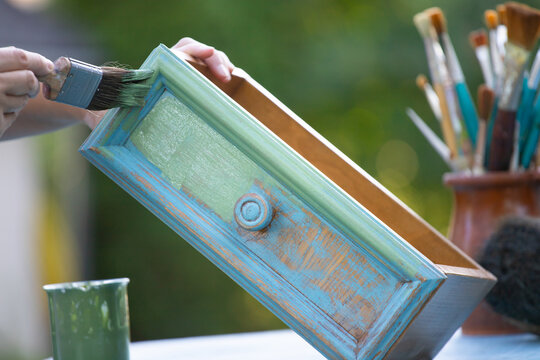 Painting a wooden furniture outdoors, an eco-friendly re-use business.