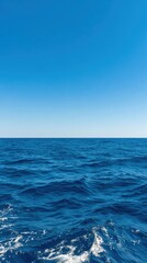 Fototapeta premium Vast ocean under clear blue sky creates a serene atmosphere, perfect for backgrounds or water-themed designs Gentle waves reflect sunlight, providing a tranquil yet dynamic element to any project