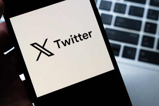 Warsaw, Poland - July 26, 2026: X Twitter logo displayed on smartphone screen held in hand against laptop keyboard background in close-up view